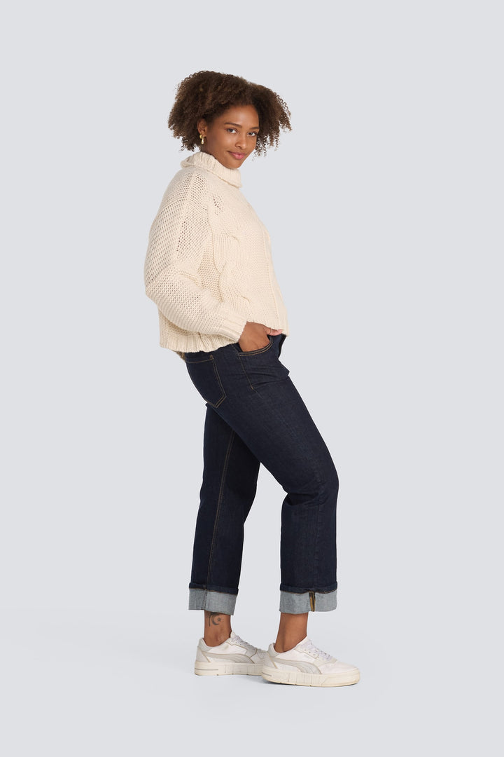 Cream chunky knit turtleneck sweater paired with dark wash cuffed jeans.