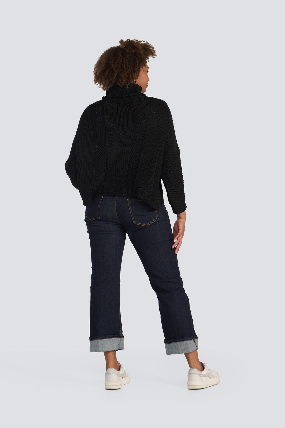 Black chunky knit turtleneck sweater paired with dark wash cuffed denim jeans.