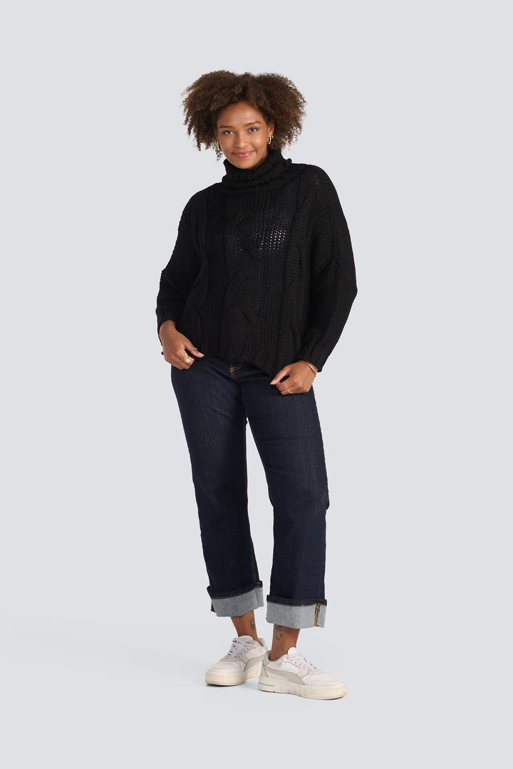 Black chunky cable-knit turtleneck sweater with long sleeves and a relaxed fit.