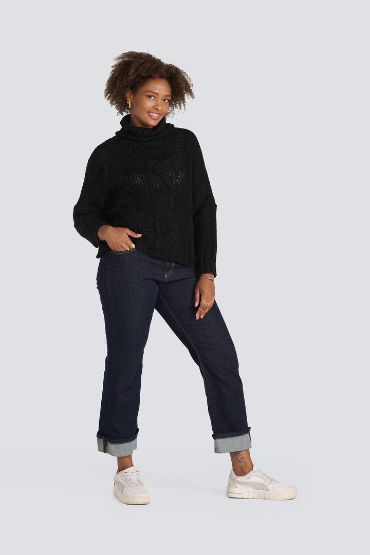 Black cable-knit turtleneck sweater paired with dark wash cuffed jeans.