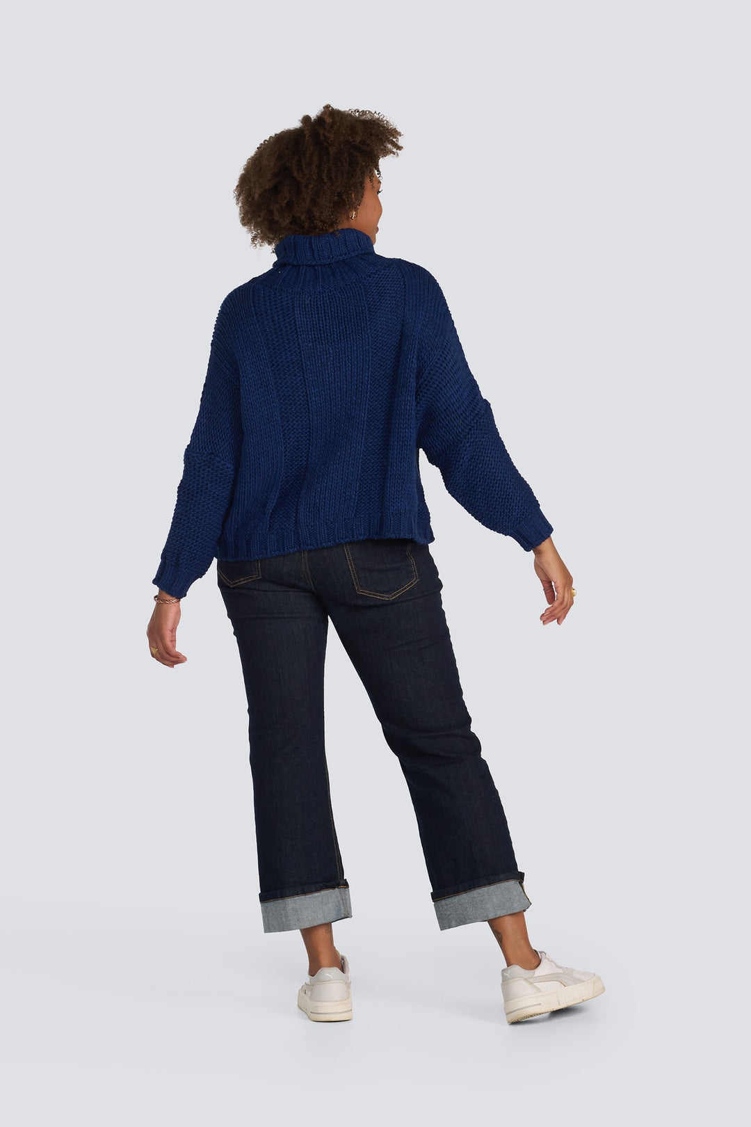 Navy blue chunky knit turtleneck sweater paired with dark wash cuffed jeans.