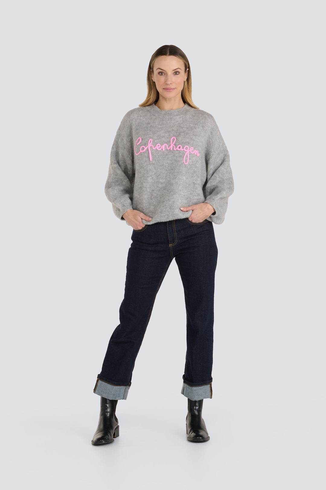 Grey knit sweater with pink cursive text reading Copenhagen across the chest.