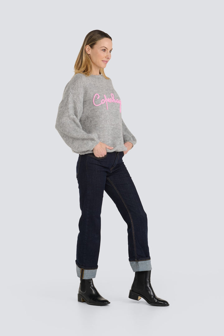 Grey knit sweater with pink script embroidery across the chest.