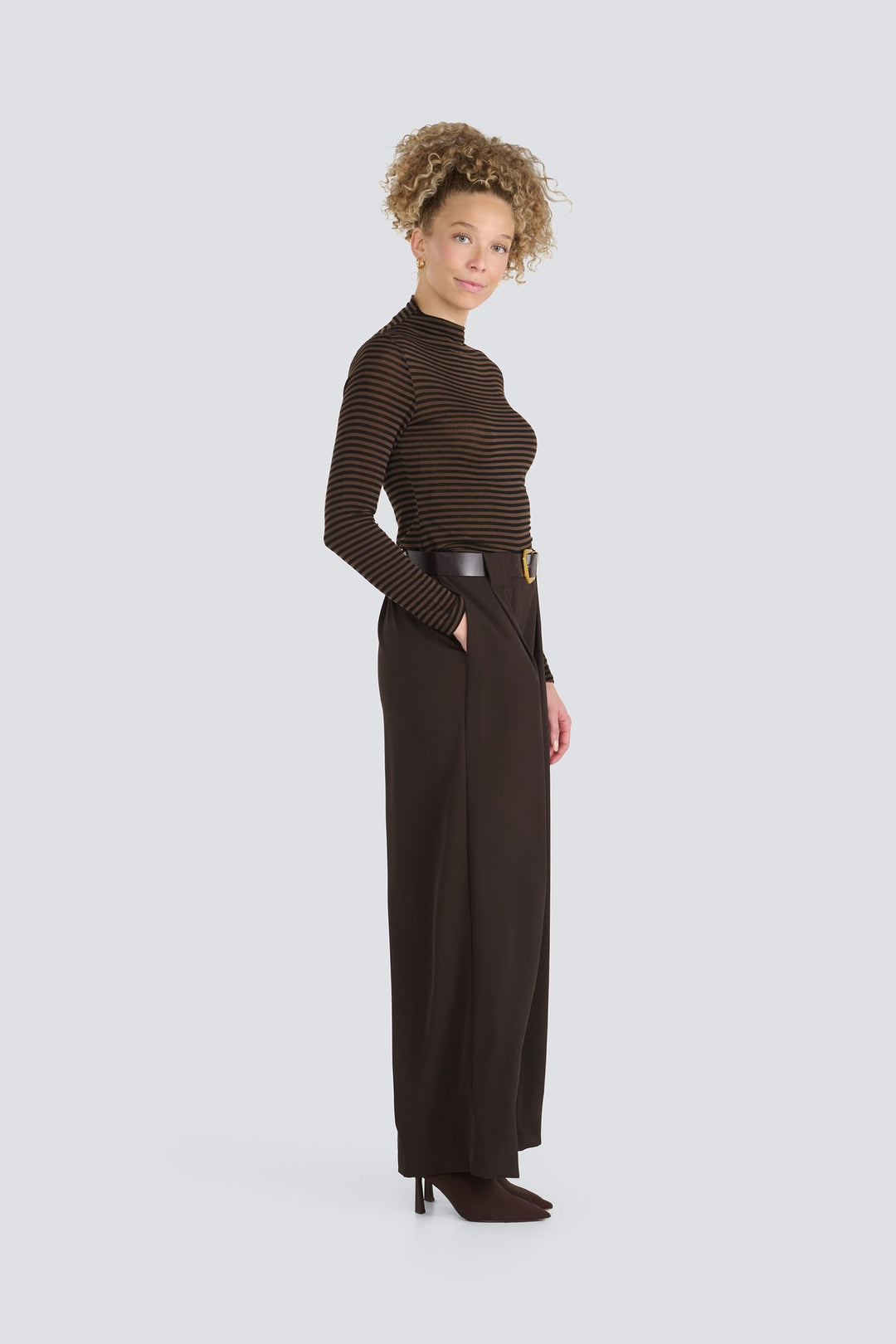 Brown striped long-sleeve turtleneck top tucked into dark brown wide-leg trousers.