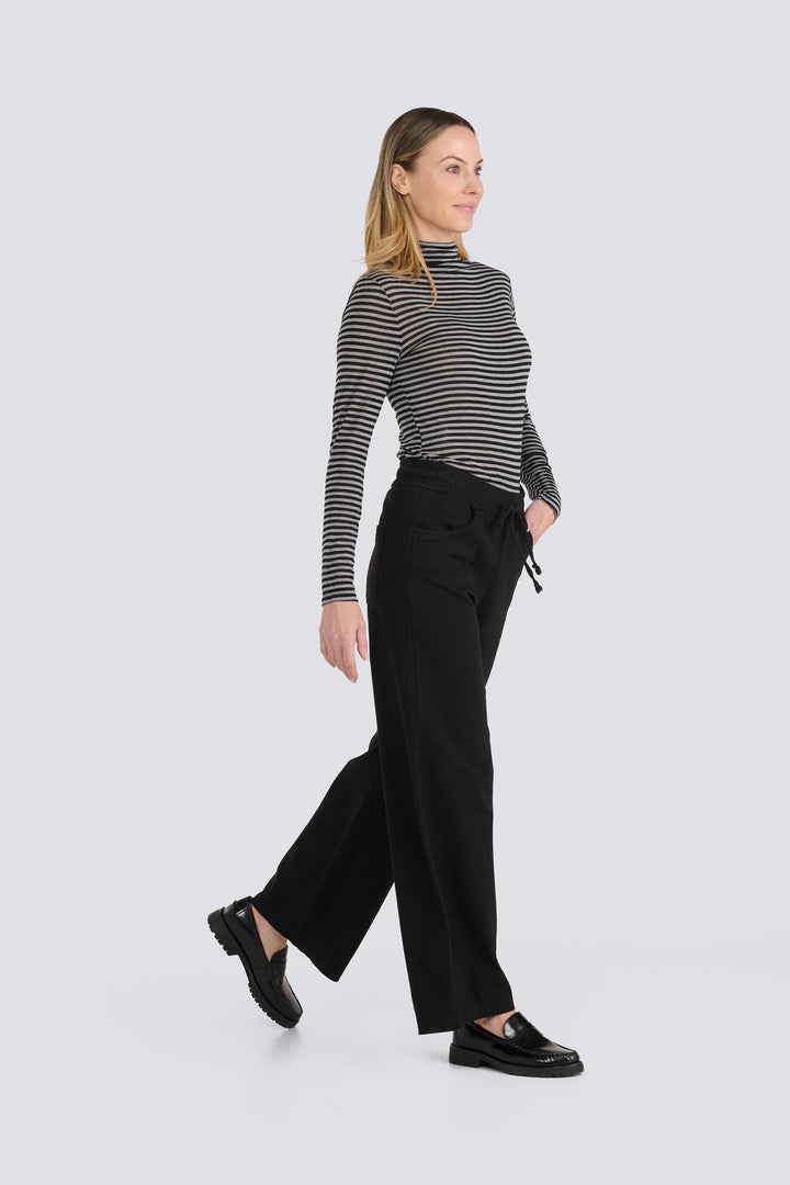 Black and grey striped long-sleeve turtleneck top paired with black wide-leg pants.