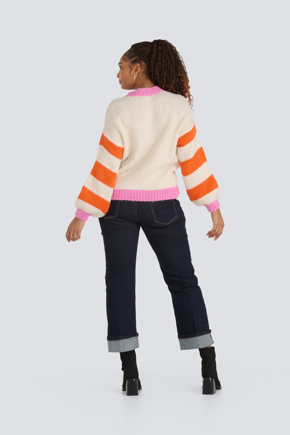 Cream knit sweater with orange striped sleeves and pink ribbed trim.