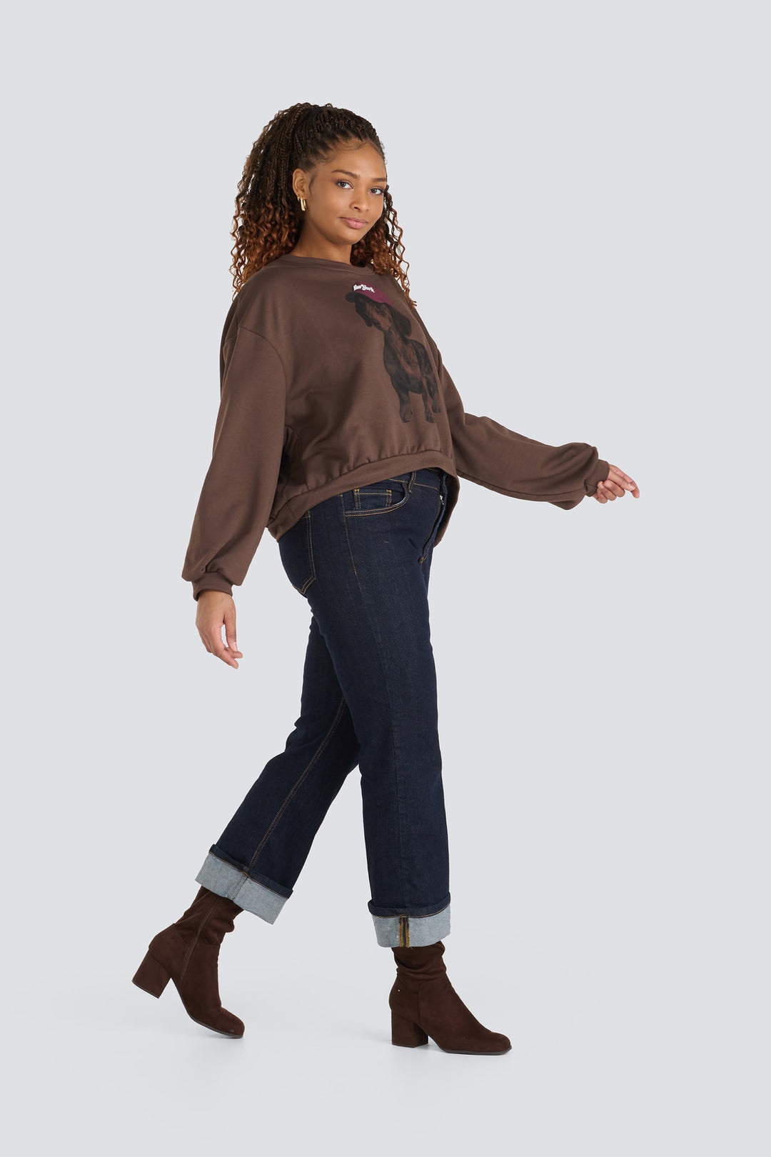Brown graphic sweatshirt paired with dark blue cuffed jeans and brown boots.