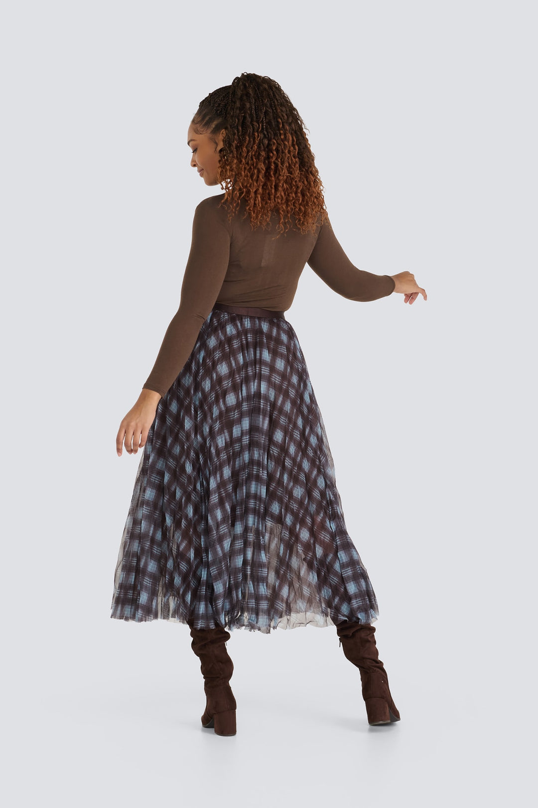 Pleated brown and blue plaid midi skirt paired with a long-sleeved brown top.
