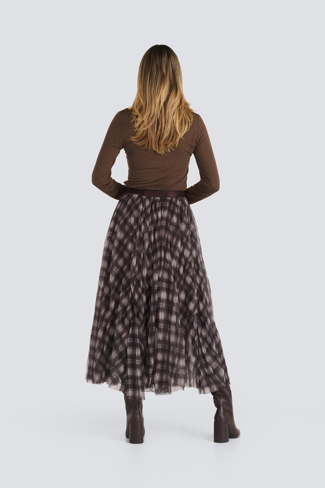 Brown long-sleeve top tucked into a pleated brown plaid midi skirt.