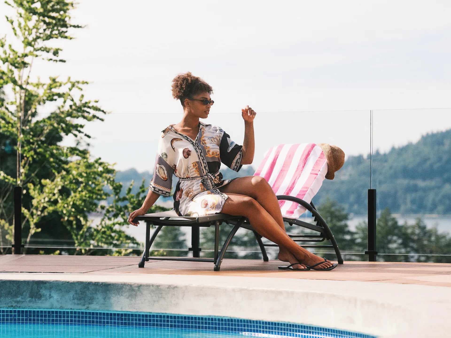 Woman sitting by a pool with a scenic background