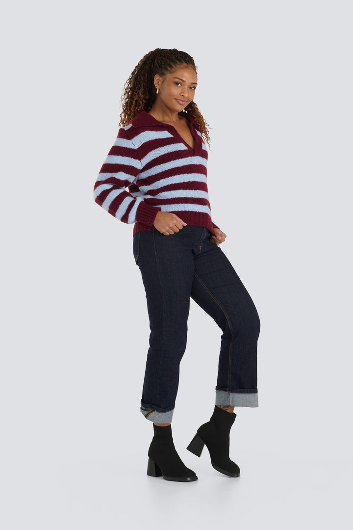 Burgundy and light blue striped knit collared sweater paired with cuffed dark jeans.