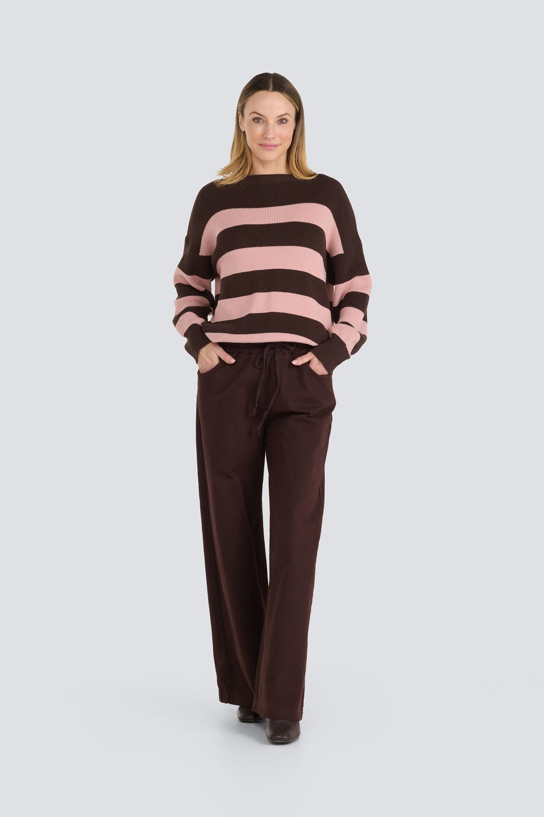 Brown and pink striped knit sweater paired with brown wide-leg drawstring pants.