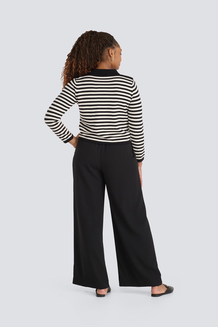 Black and cream striped knit sweater paired with black wide-leg trousers.