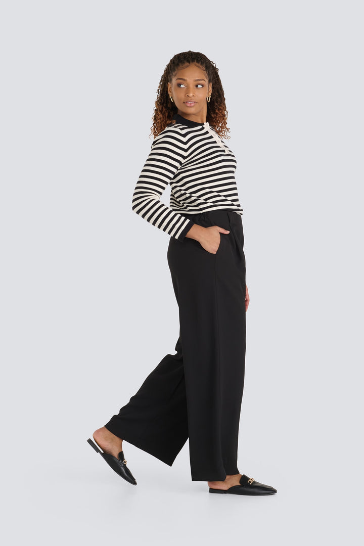 Black and cream striped long-sleeve polo sweater styled with black wide-leg pants.