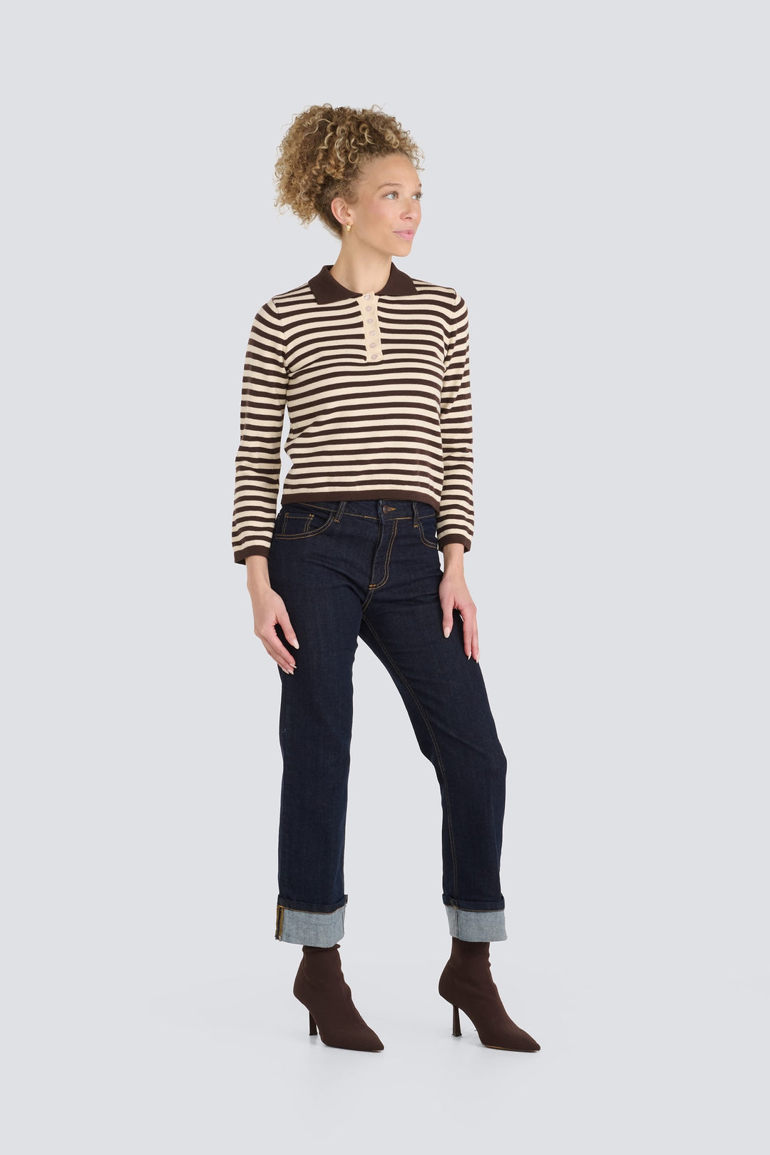 Brown and cream striped knit polo sweater paired with dark cuffed jeans.