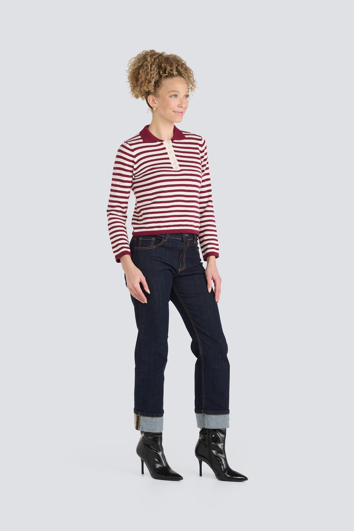 Burgundy and cream striped long-sleeve knit polo sweater worn with dark cuffed jeans.