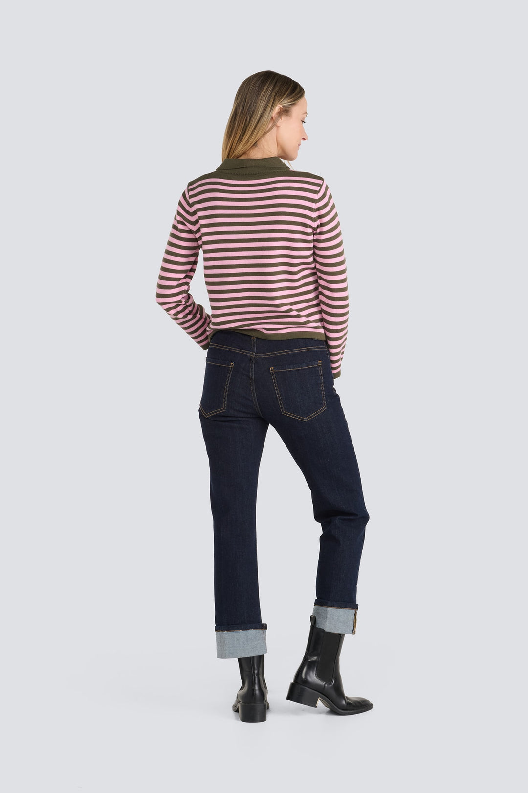 Pink and olive green striped long-sleeve sweater paired with dark wash cuffed jeans.