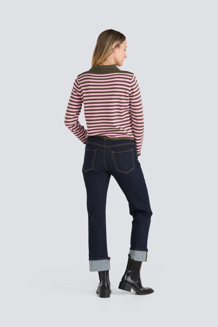 Pink and olive green striped long-sleeve sweater paired with dark wash cuffed jeans.
