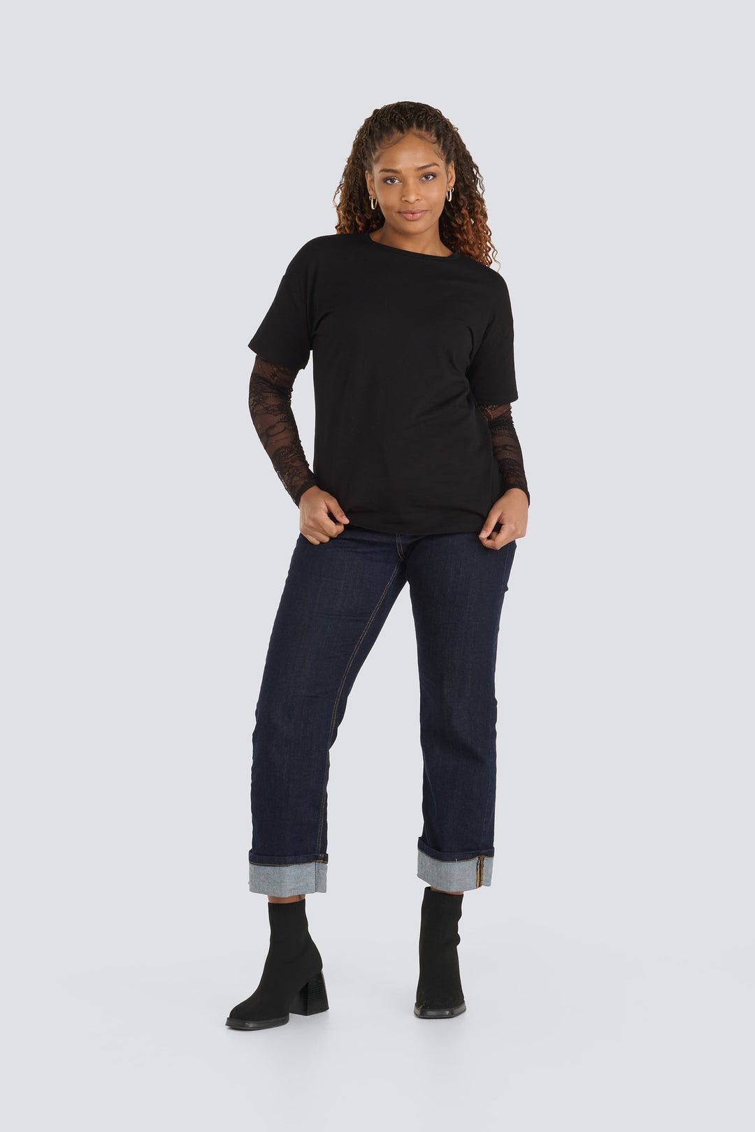 Black crewneck t-shirt featuring sheer lace long sleeves and dark-wash cuffed jeans.